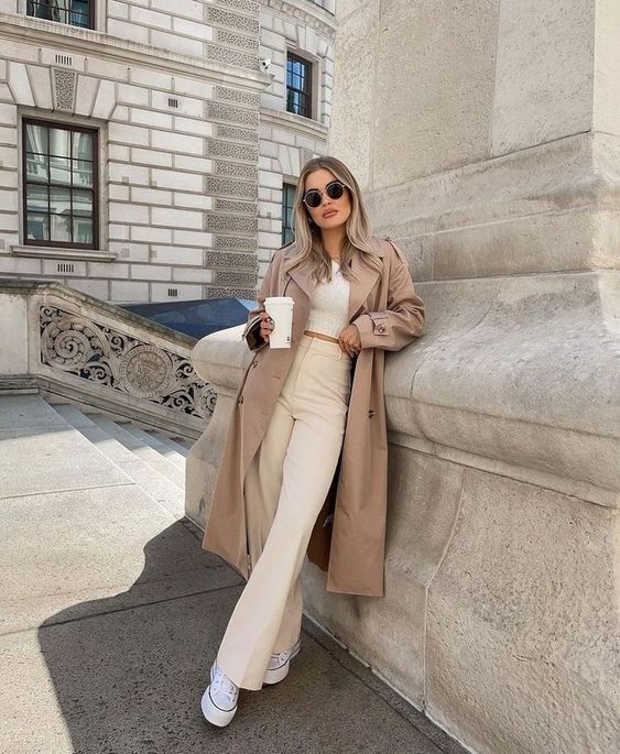 trench coat over a white cropped sweater and cream trousers